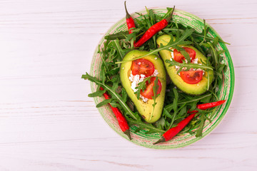 Avocado stuffed with feta cheese, arugula and tomatoes