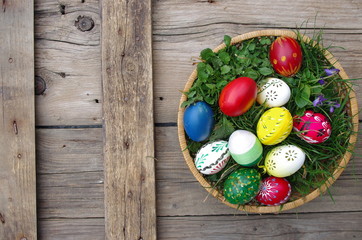 Easter eggs in the basket on rustic wooden background.