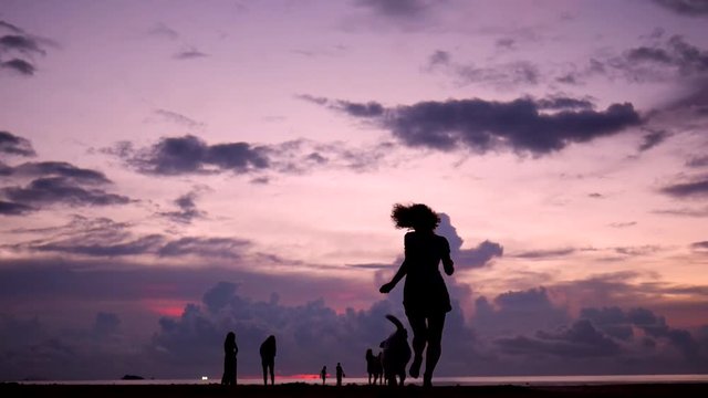 Pretty Young Girl Running with her Dog at Beautiful Sunset on the Beach. HD Slowmotion. Phangan, Thailand.