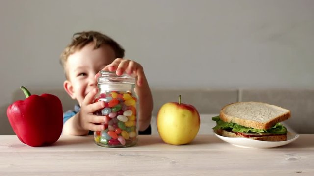 cute little boy takes jar of colorful candy