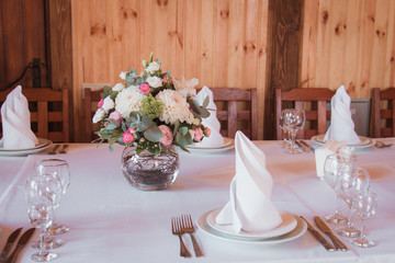 Stylishly decorated wedding table with flowers, candles, rose petals  in pink colors. Flower arrangement