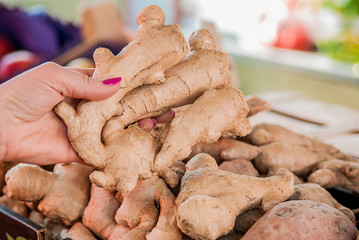 Young woman buys ginger at the market. woman choose ginger in supermarket. woman picking fresh produce at the market