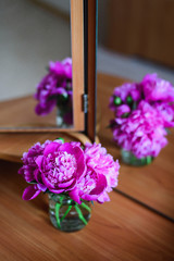 close-up pink peonies in glass jar on table with mirror reflection, congratulations for everyday concept