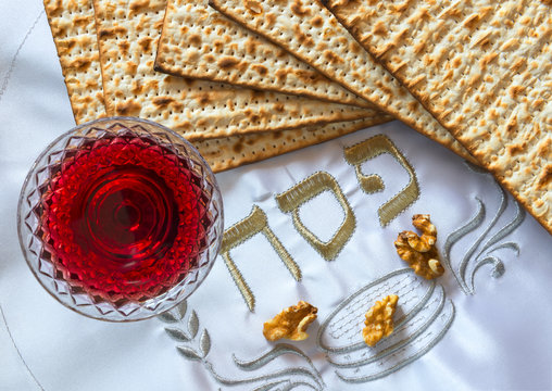 Traditional food (matzah) and drink (red wine) for Jewish Passover Holiday, placed on a white festive serviette with Hebrew word pesah or  Passover