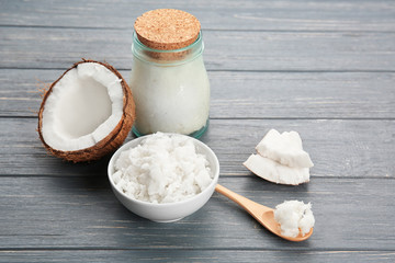 Spoon, bowl and glass jar with fresh coconut oil on wooden background