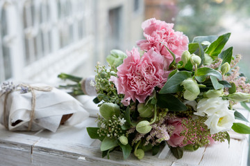 Bouquet of pink carnations and Hellebore flowers lying on white background.