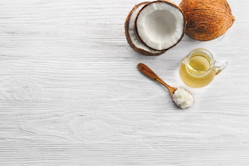 Coconut and kitchenware with oil on wooden background