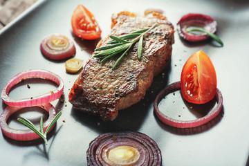 Delicious grilled steak with aromatic rosemary, tomatoes and onion, closeup