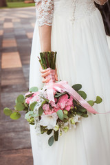 Tender wedding bouquet of pink hydrangea and gladiolus flowers with eucalyptus leaves  in bride's hands.Close-up bunch of flowers. Bridal accessories.