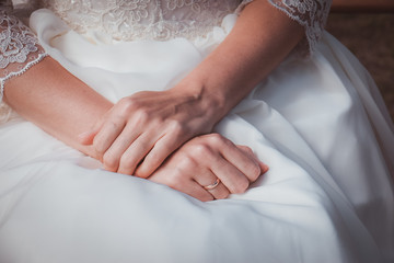 Hands of the bride on white wedding dress with lace. Wedding details. Close up