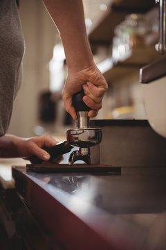 Female barista tamping coffee in cafe