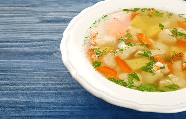Plate with chicken soup on wooden table