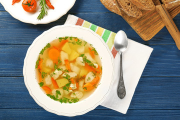 Plate with chicken soup on wooden table