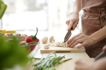 Keuken foto achterwand Koken Vrouw die champignons snijdt tijdens kooklessen