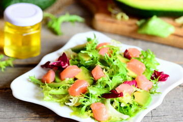 Salmon, avocado and lettuce mix salad. Home salad with slices of smoked salmon, fresh avocado and lettuce leaves mix on a plate. Delicious and healthy appetizer. Closeup