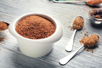 Bowl and spoons with brown sugar on wooden table