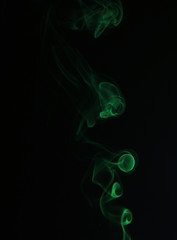 Fototapeta premium Swirl of green smoke on black background