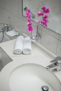 Beautiful and modern interior design bathroom, pink orchids closeup and towels