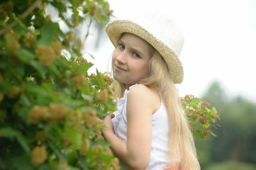 Fototapeta premium Little blonde girl wearing a hat in the garden.