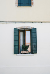 Beautiful facade in Veneto, Burano Island. Decorated textured grungy and colorful wall with an old window in the middle