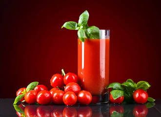 Glass of tomato juice with red small tomatoes