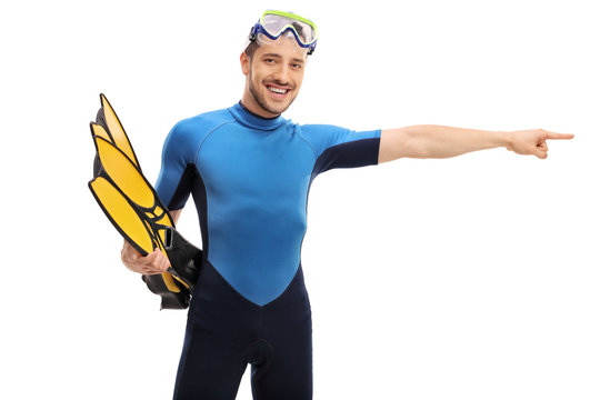 Guy in a wetsuit with snorkeling equipment pointing right
