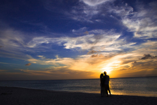 Silhouette of unrecognizable romantic couple at beach at sunset