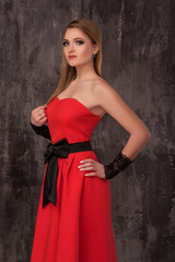Beautiful happy young woman in red dress on grey background