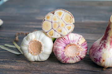 Whole and cut fresh young garlic bulbs on wooden table. Closeup.