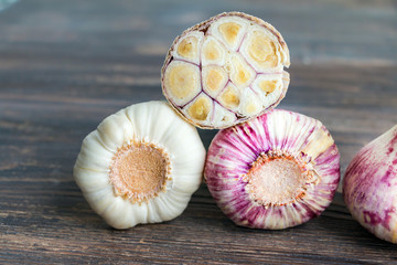 Whole and cut fresh young garlic bulbs on wooden table. Closeup.