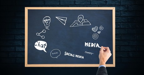 Cropped image of hand writing on blackboard against brick wall