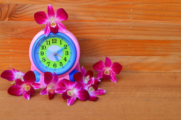 Alarm Clock and flowers purple orchid  on wooden floor board  spring time concept