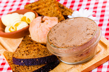 Chicken liver pate, toasted bread, butter and baked apple on wooden board