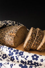 Whole wheat sliced bread closeup , on wooden surface with floral kitchen towel.