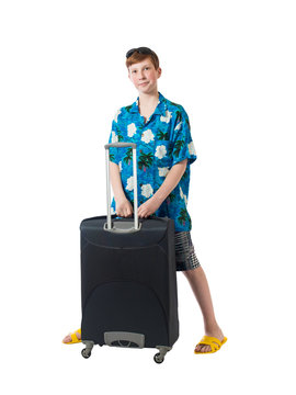 Young boy in a shirt and shorts is standing near a large suitcase and looking expectantly on a white background
