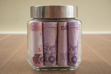 A tip or saving jar filled with Thailand bills.