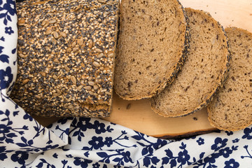 Whole wheat sliced bread closeup , on wooden surface with floral kitchen towel.
