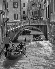 A gondola and a motorboat near the Ponte San Paternian bridge, on the Rio de San Luca on a sunny summer day, Venice, Italy, in black and white © Marco Taliani