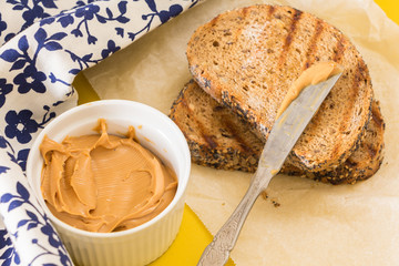 Spreading peanut butter on whole wheat grilled  bread slice