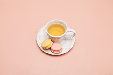 Cup of tea with macarons on pink background