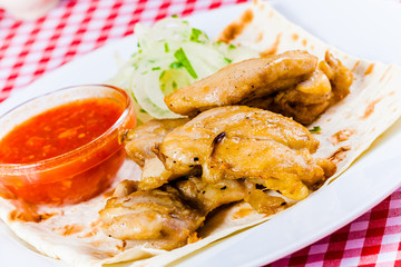Grilled chicken with tomato sauce,onion, pita bread on white plate