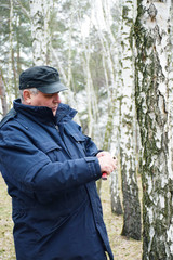 Mature man sharpening the knife in the birch forest