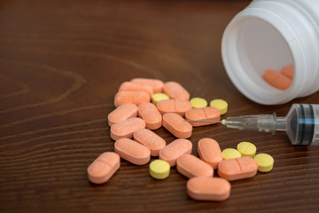 medicine pill with and syringe on wood background.