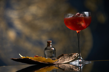 Fresh branded red alcoholic cocktail with a small bottle for alcohol and a red marmalade snack on a black stone bar counter.  Concept of alcoholic and non-alcoholic bar beverage.