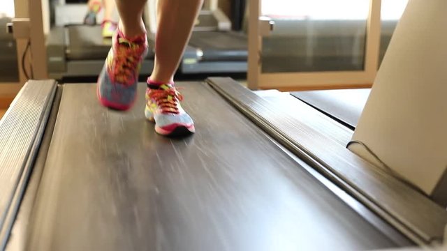 Colorful gym shoes of woman on gym tapis roulant. Fast training indoor. Healthy active lifestyle . Slow motion front view.
