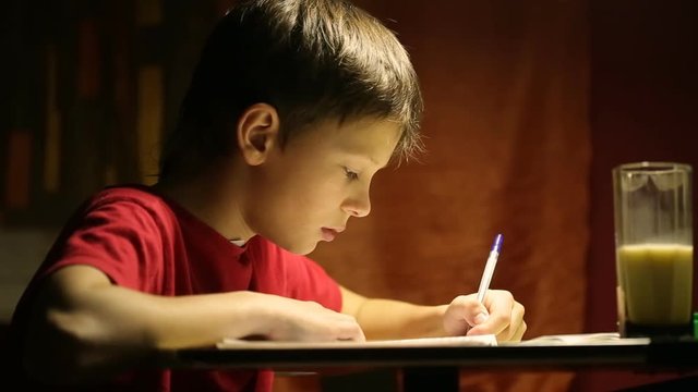 The boy at the desk writes in a notebook