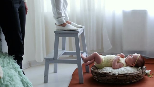 photo shoot of a newborn baby in a basket in the studio window
