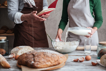 Loving couple bakers standing near bread and cooking.