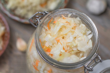 Homemade sauerkraut village. Fermented cabbage. Vegan salad rustic style glass jar or ceramic pottery bowl. Fermented food great for good health. Traditional rustic winter food. Top view.