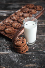 Cookies on desk on dark wooden table with milk